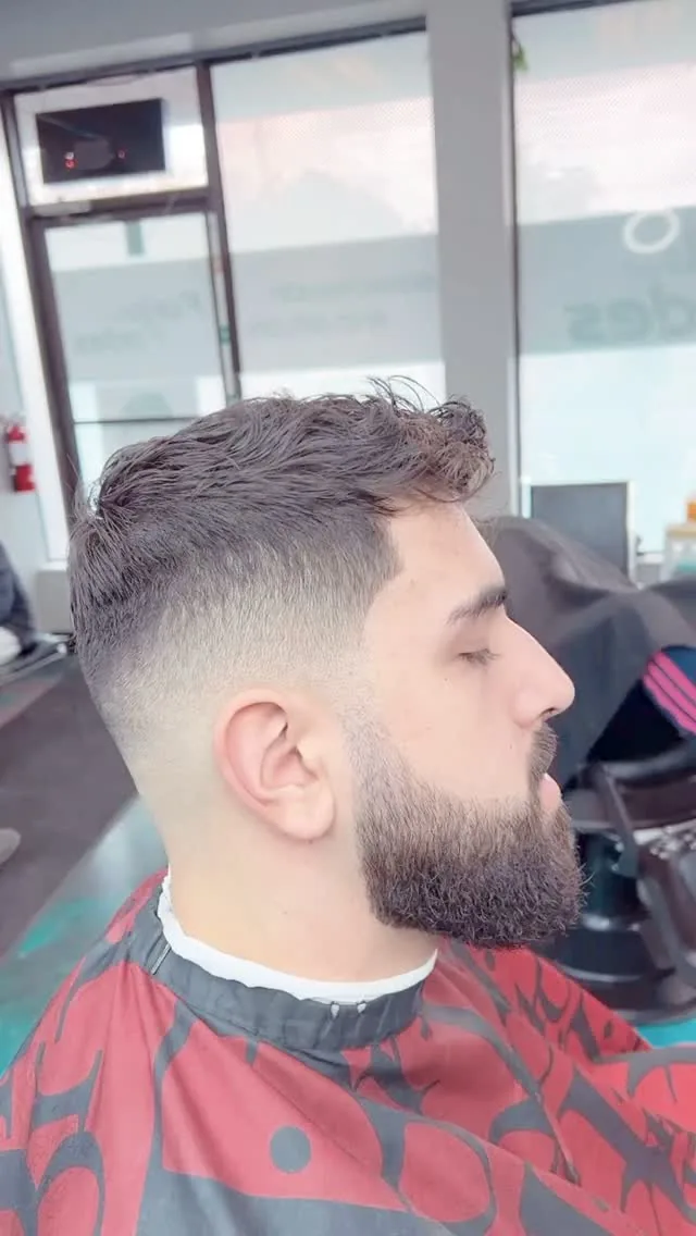 Mid drop fade with a textured top and full beard, side profile at Furious Fades