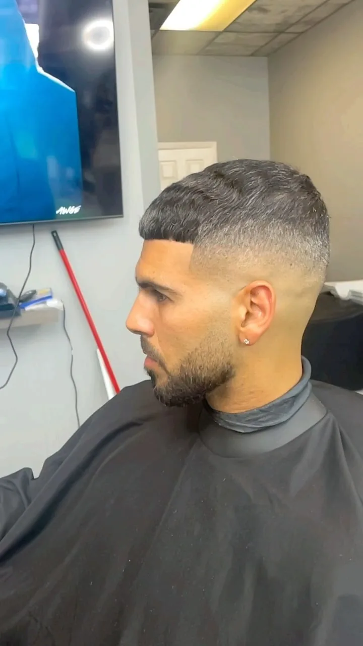 Mid fade with a short crop top and beard, side profile
