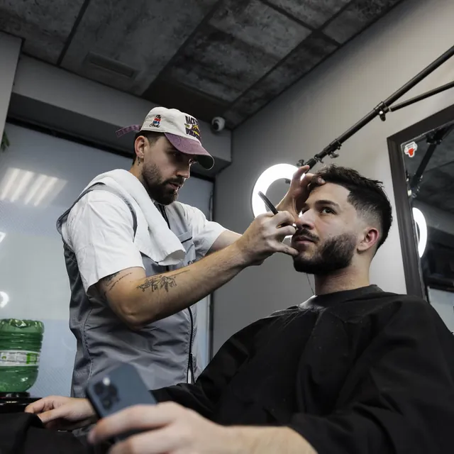 Furious Fades barber shaping a client's beard with a straight razor, client with a fade and full beard