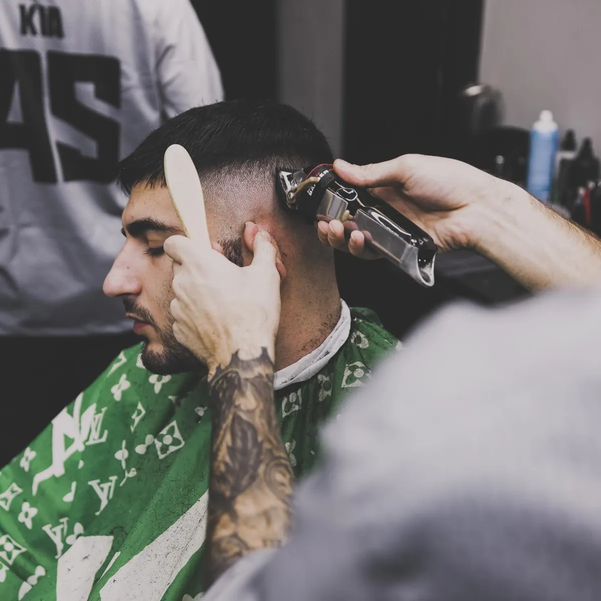 Furious Fades barber cutting a skin fade with clippers, client in a green cape
